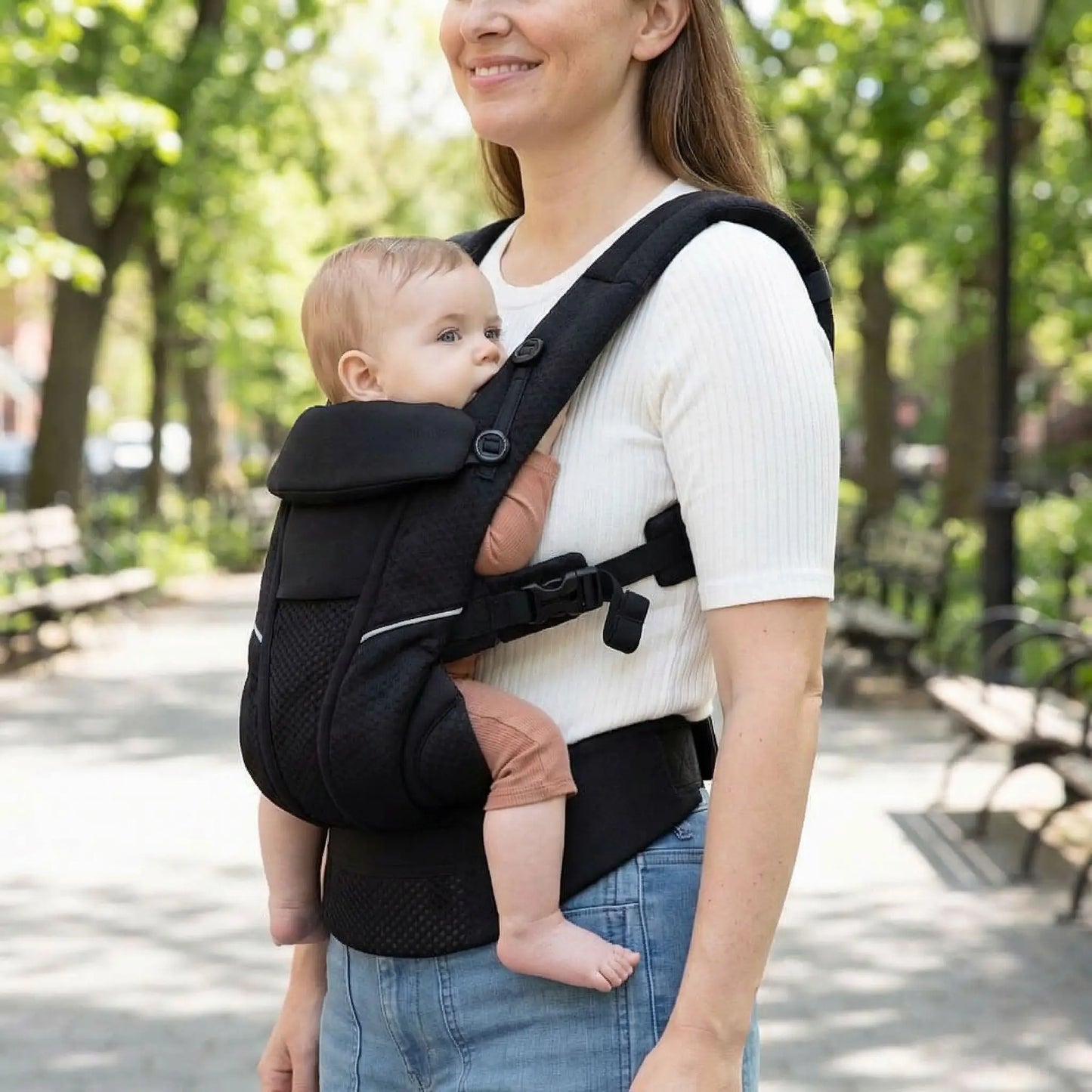 maman marchant avec son bebe dans un porte bebe ergonomique noir lors dune promenade