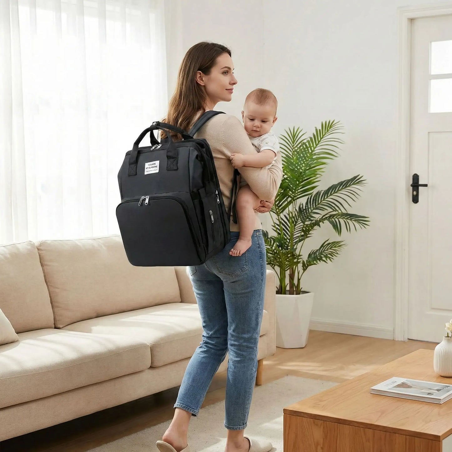 Sac a dos a langer bebe noir porte au dos par une maman sortant de son domicile avec bebe