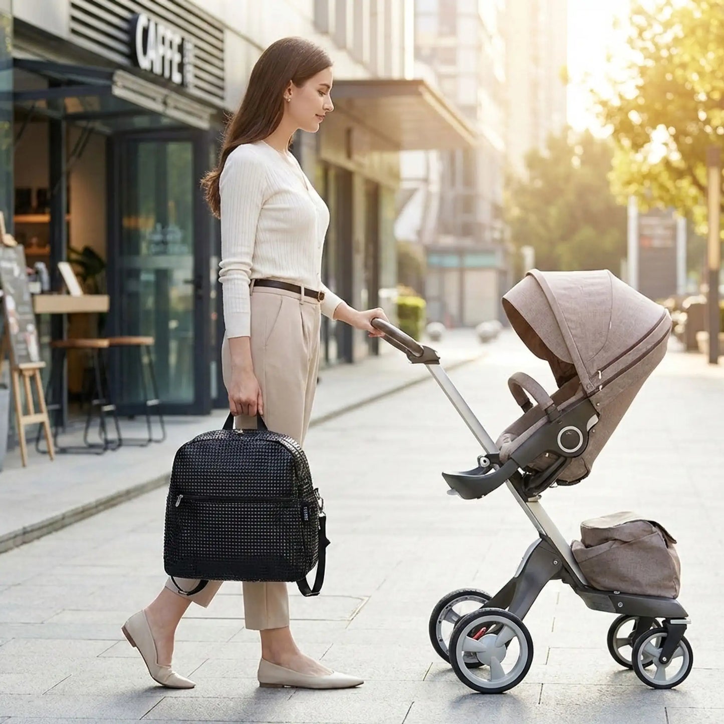 sac a langer noir porte a la main par une maman en promenade avec bebe en poussette