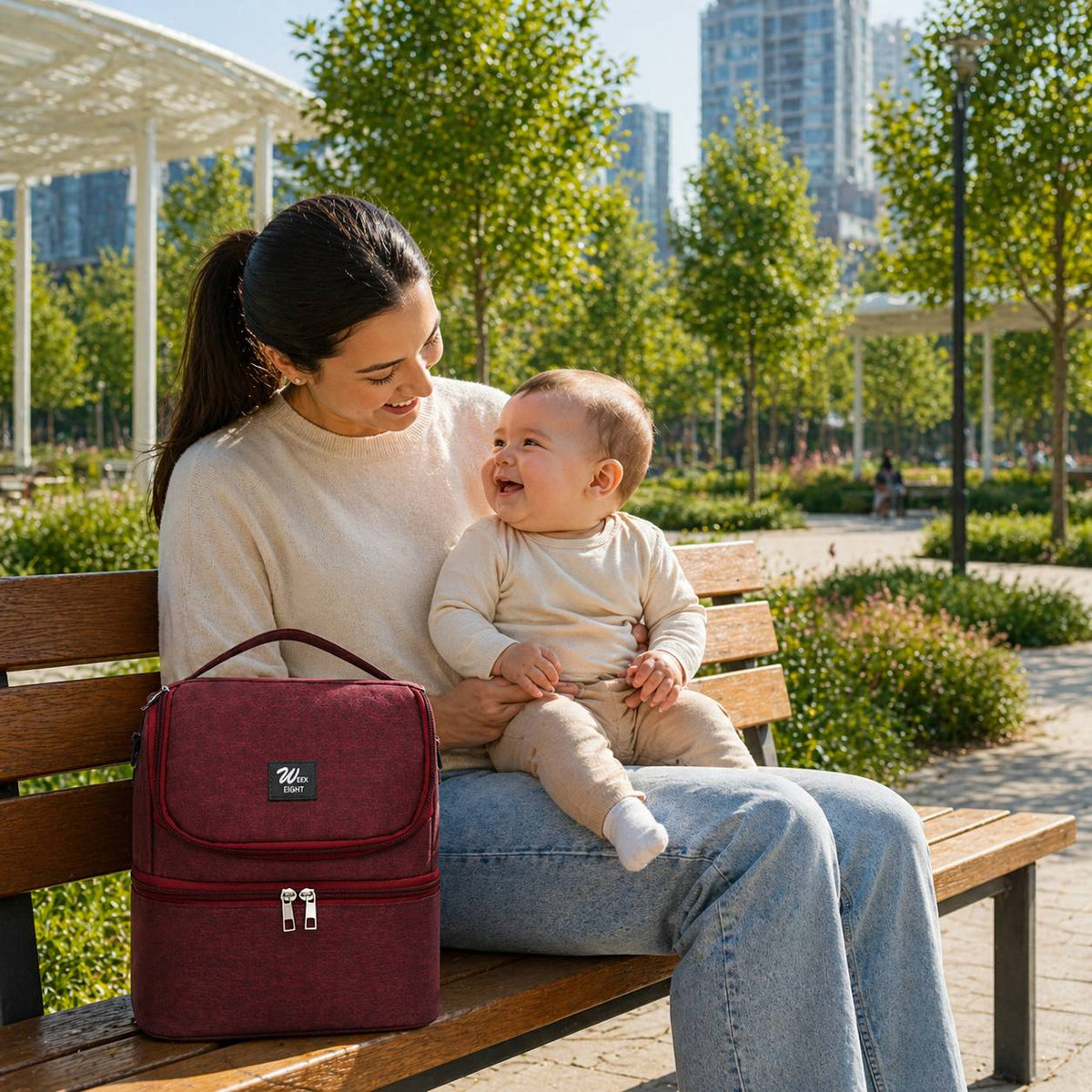 Sac isotherme biberon rouge pose sur un banc avec maman et bebe