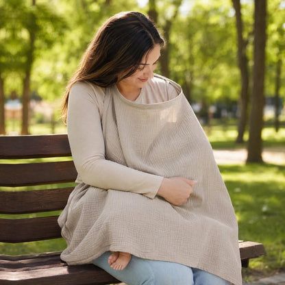 Cape d'allaitement beige utilisée par une maman avec bébé sur un banc au parc