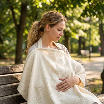Cape d'allaitement couvrante portée par une maman assise avec bébé dans un parc