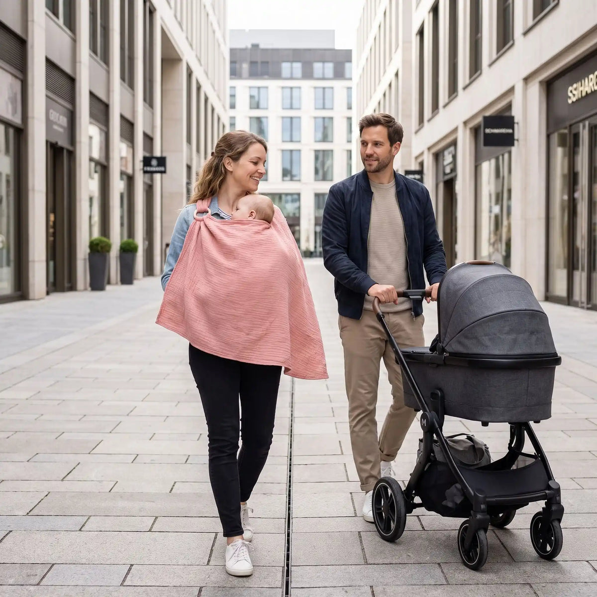 Cape d'allaitement portée par une maman lors d'une promenade en famille avec poussette