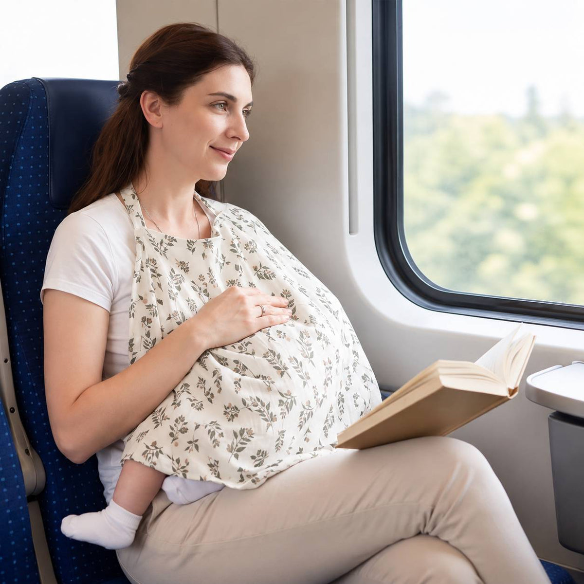 Cape d'allaitement portée par une maman avec bébé pendant un trajet en train