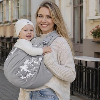 Echarpe de portage avec bébé confortablement installé contre sa maman en ville