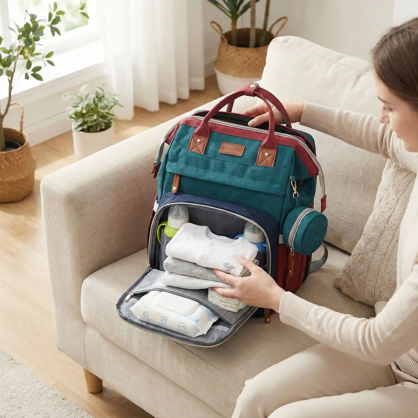 Une maman est au salon et montre un sac a langer avec berceau integre et poche ouverte