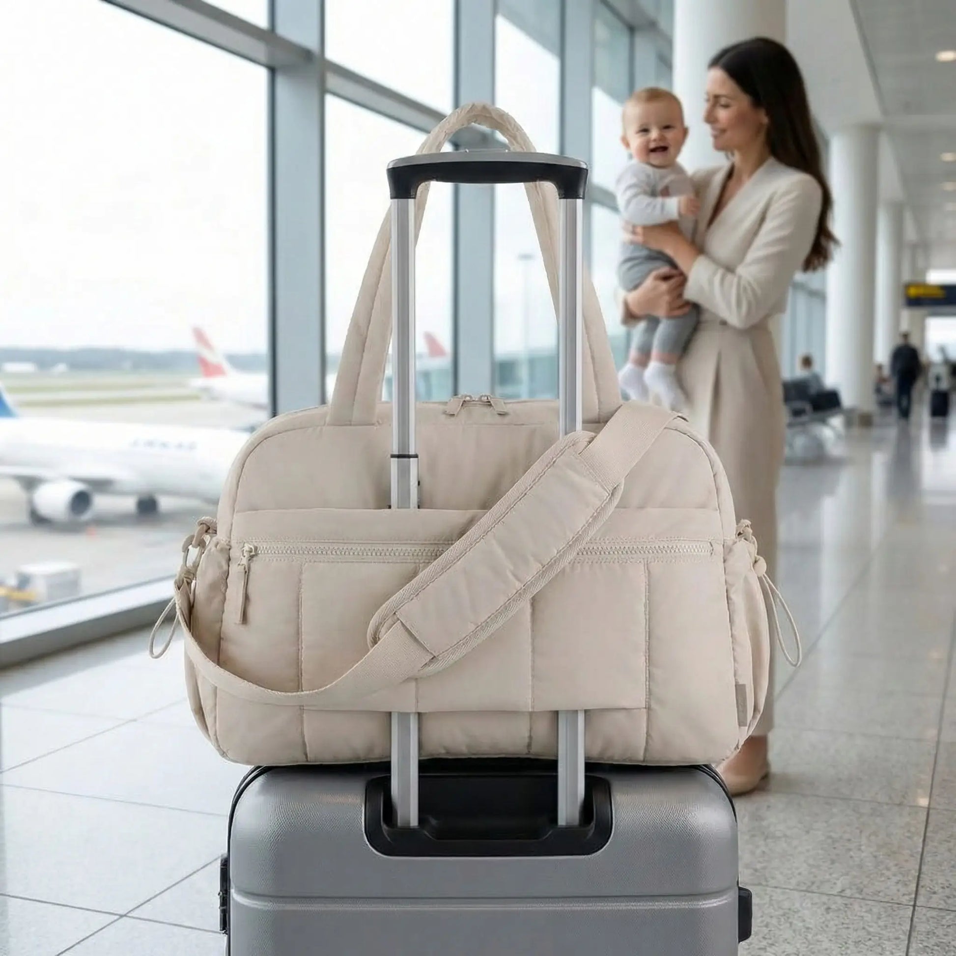 maman et bebe a laeroport avec sac a langer portable cabine beige fixe sur valise trolley