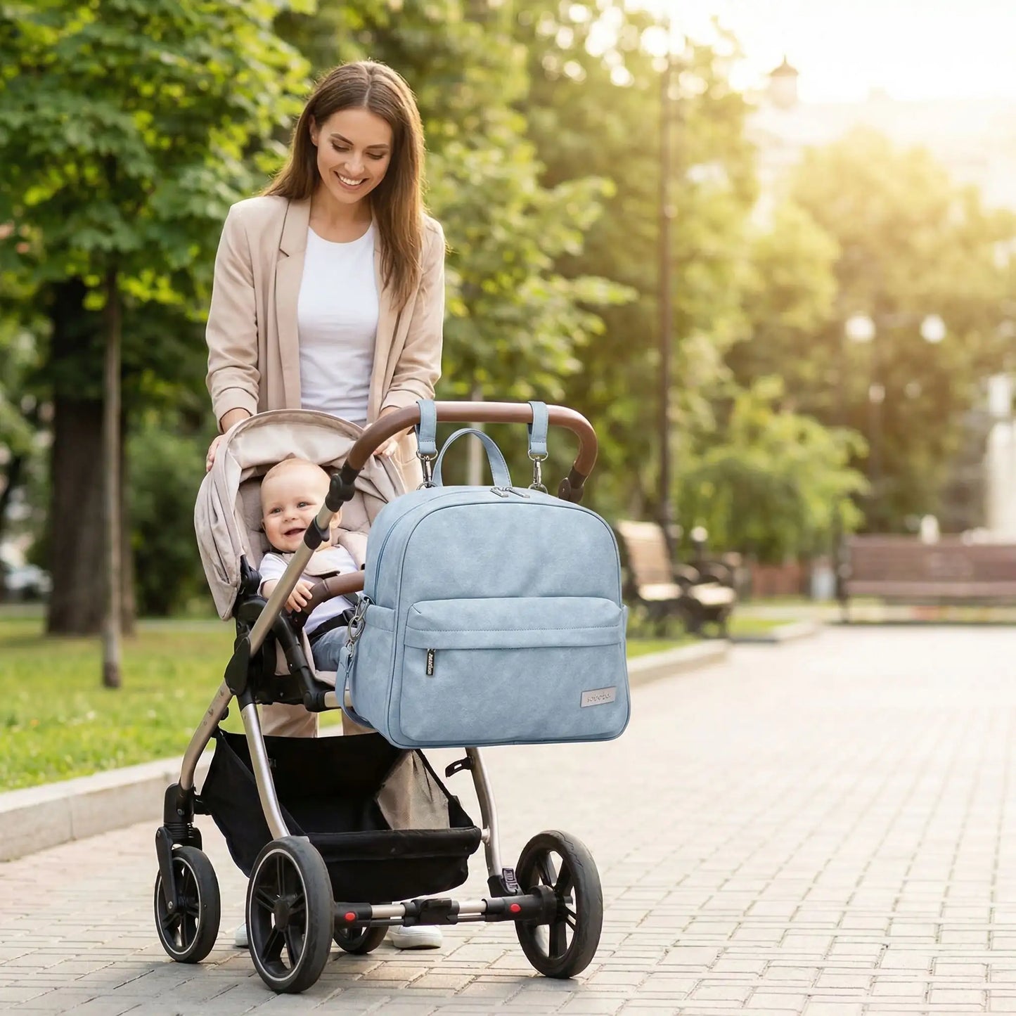 Maman et bebe dans une poussette au parc avec un sac a dos a langer accroche a la poussette