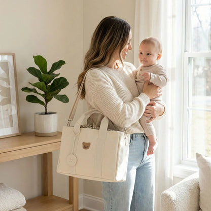 maman portant bebe en bras avec sac a langer portable compact creme a epaule