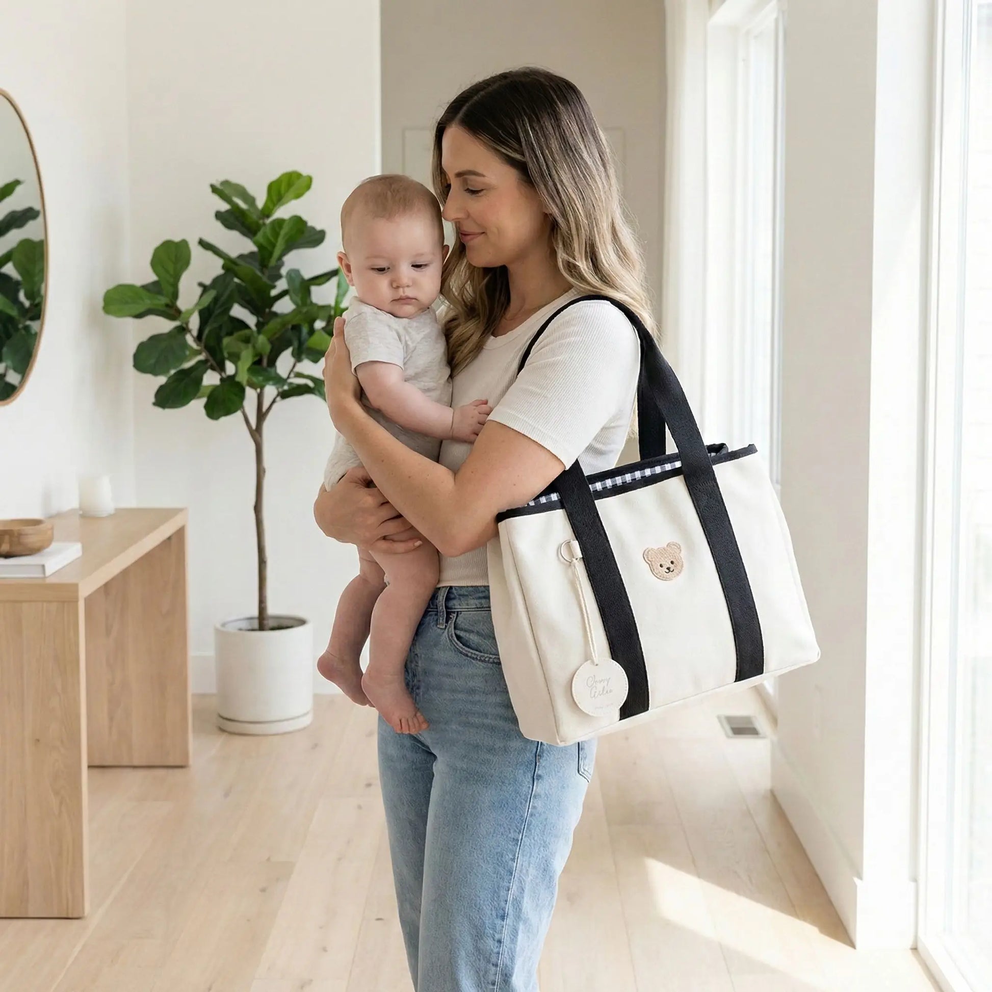 maman portant bebe avec sac a langer portable compact noir et blanc a epaule