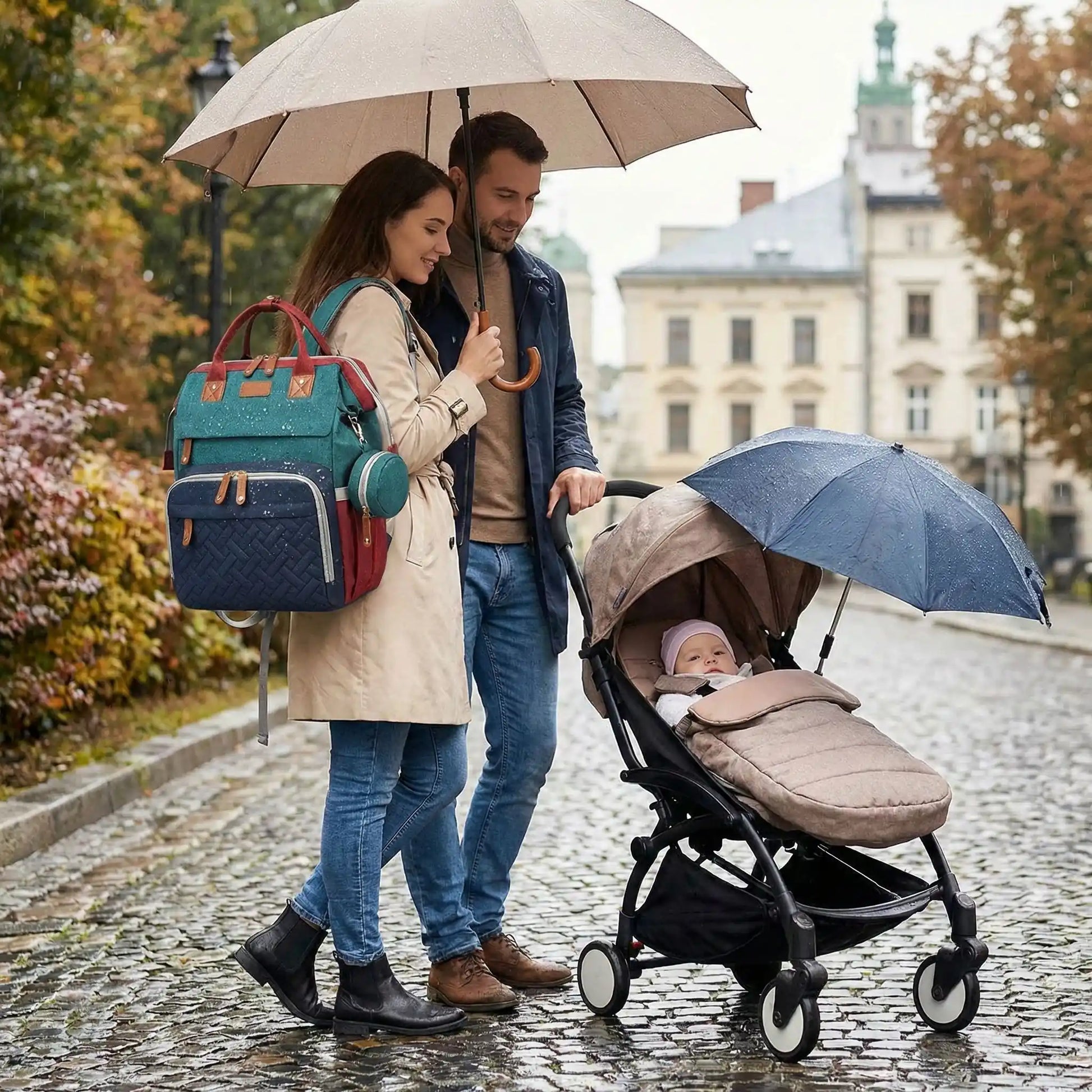 Un papa et une maman sont au parc sous la pluie avec leur bebe et un sac a langer avec berceau integre