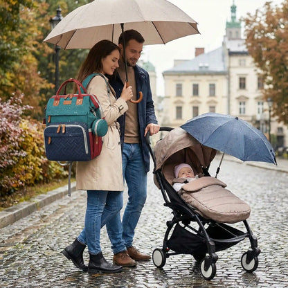 Un papa et une maman sont au parc sous la pluie avec leur bebe et un sac a langer avec berceau integre