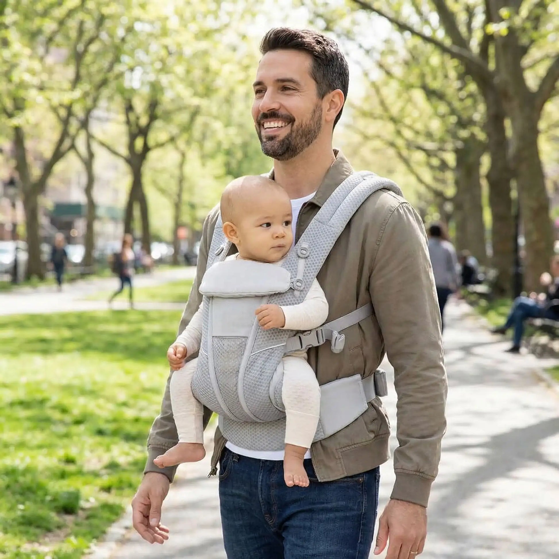 papa portant son bebe dans un porte bebe ergonomique pendant une balade au parc