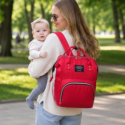 Sac a dos a langer porte par maman en promenade avec son bébé 