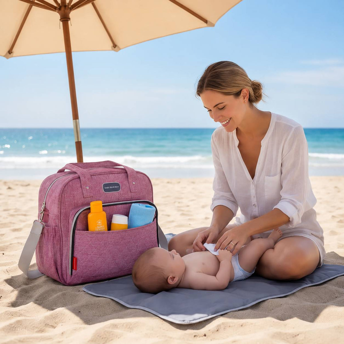 Sac a langer avec tapis de change rose utilisé par une maman et son bébé à la plage