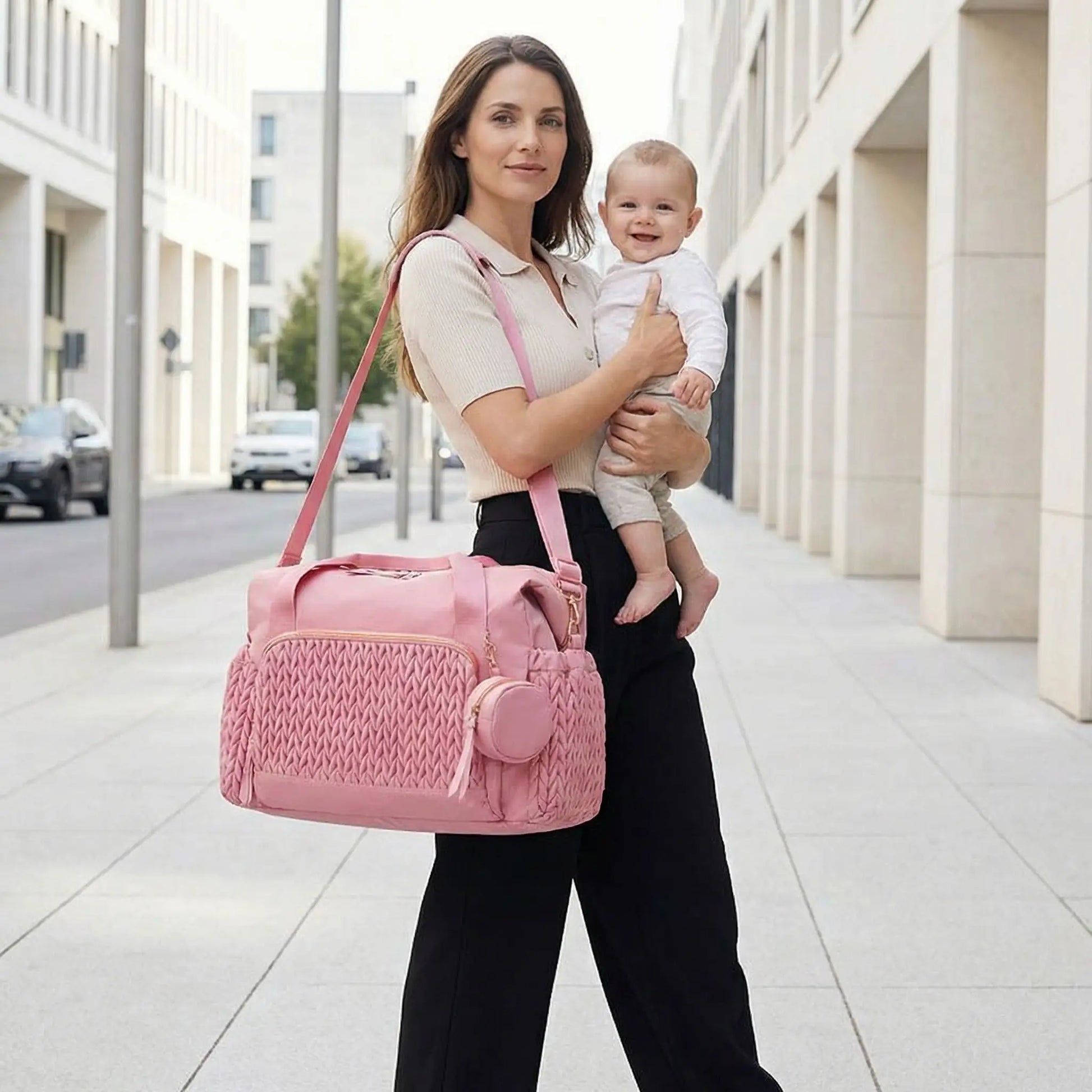 Sac a langer bebe bandouliere rose grande capacite porte par maman dans rue lumineuse